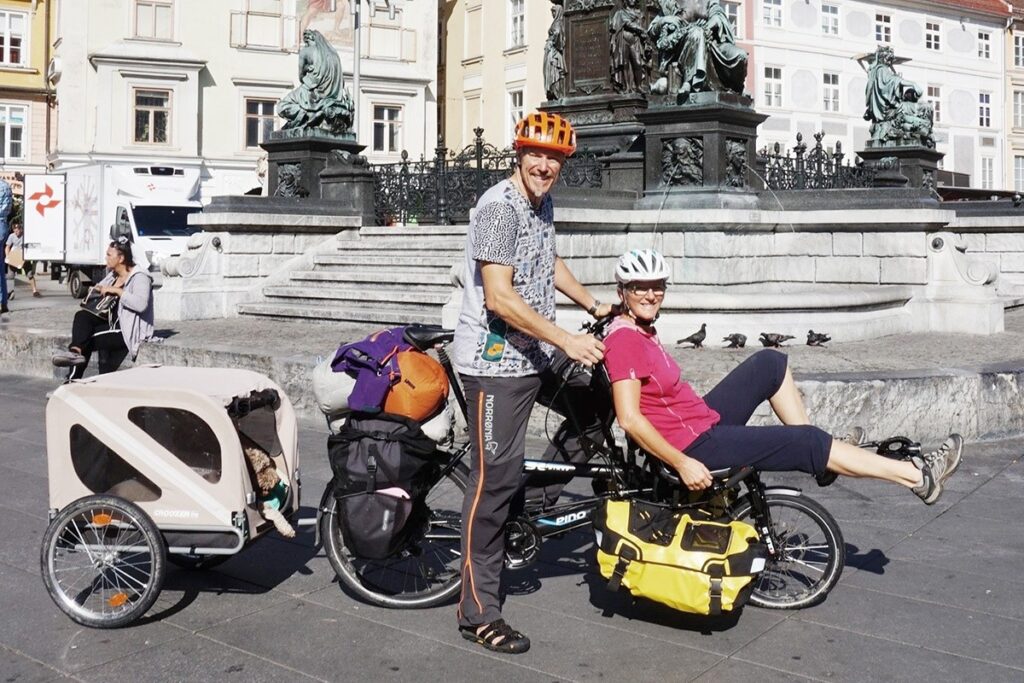 Ein Paar auf einem Spezial Tandem Bike mit Hund im Anhänger