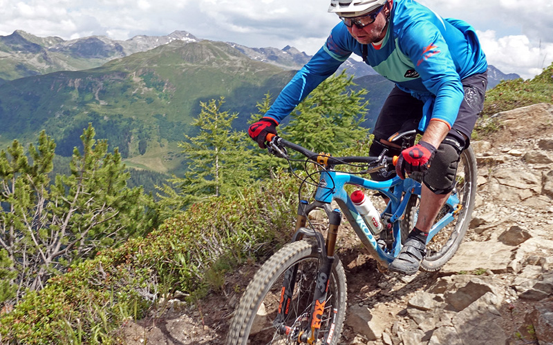 Ein Mann fährt mit seinem Koba Mountainbike den Berg herab